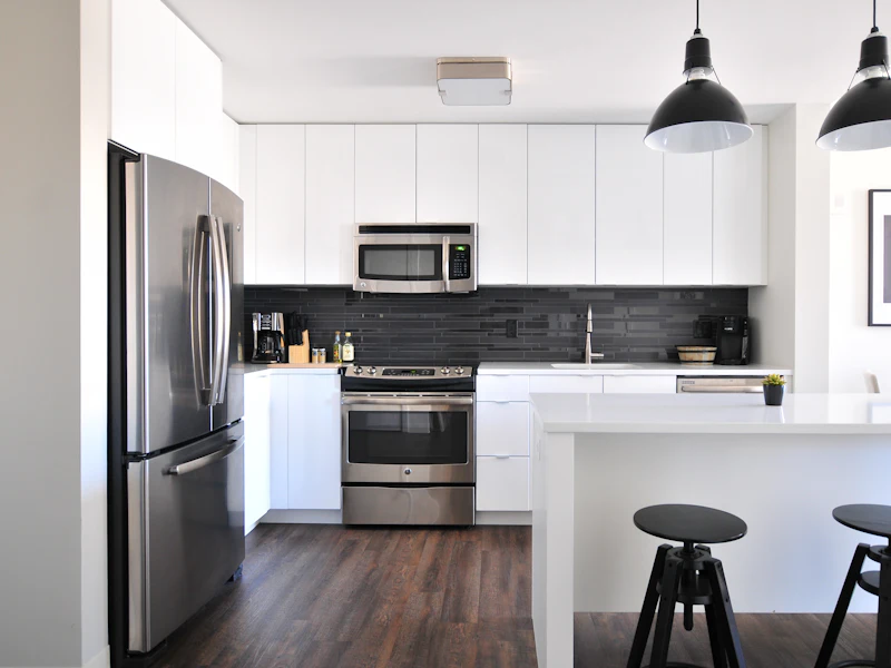 Clean white kitchen with stainless appliances and clear countertops