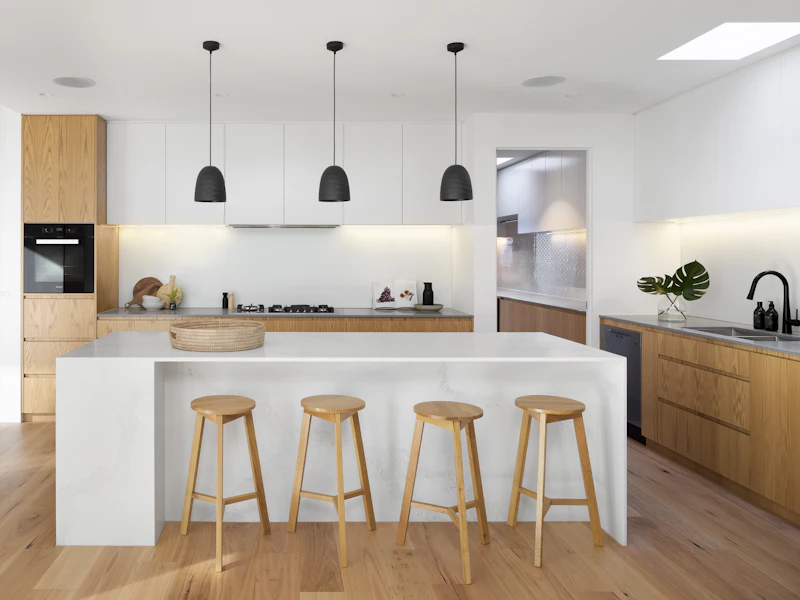 Newly renovated kitchen with clean white countertops and wood stools